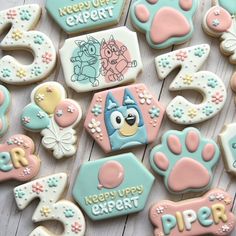 some decorated cookies are laying on a white wooden table with the words happy puppy's birthday written in blue and pink