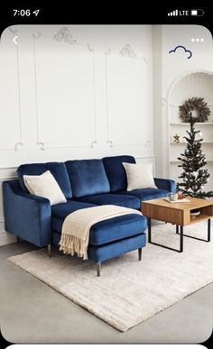 a living room with a blue couch, coffee table and christmas tree