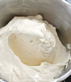 a metal bowl filled with whipped cream on top of a table