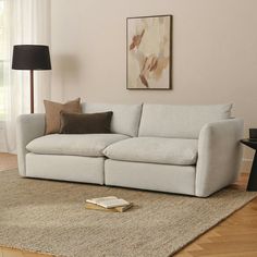 a white couch sitting on top of a wooden floor next to a lamp and rug