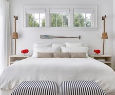 a bed with white linens and striped pillows