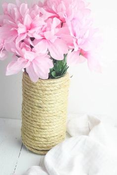 pink flowers are in a rope wrapped vase