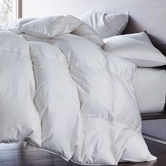 an unmade bed with white sheets and pillows