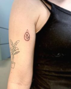 a woman with a tattoo on her arm and a potted plant in the background