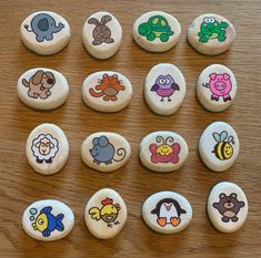 twelve buttons with cartoon characters on them sitting on a wooden table together, all decorated in different colors and sizes