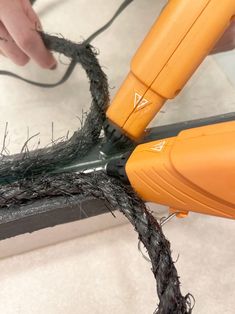 a person is using a hair dryer to cut up some black wire on the floor