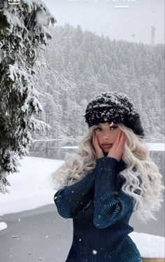 a woman with long blonde hair wearing a black hat and blue dress in the snow