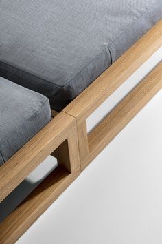 a wooden bench with grey cushions on it