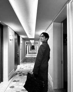 a man standing in an empty hallway holding a briefcase