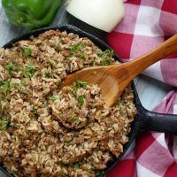 a skillet filled with rice and meat on top of a checkered table cloth