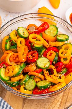 a glass bowl filled with peppers and cucumbers