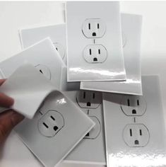 a person is holding some electrical plugs in front of the white wall outlets