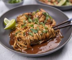 a plate with noodles, meat and sauce on it next to some chopsticks