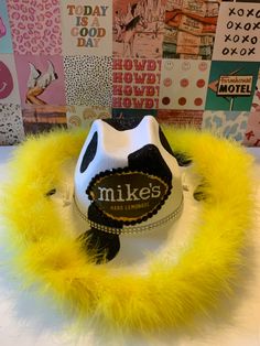 a hat with yellow feathers on top of a white table next to posters and signs