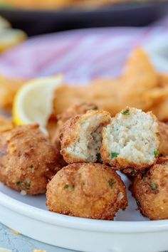 some fried food on a white plate with lemon wedges