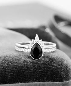 a black and white photo of a ring with a pear shaped diamond in the center