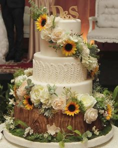 a wedding cake with sunflowers and greenery on top