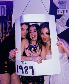 three women are posing in front of a photo frame