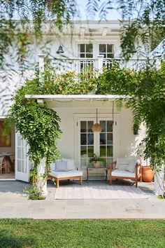 a white house with lots of greenery on the front door and patio area,