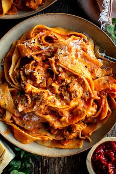 two plates filled with pasta and sauce on top of a wooden table