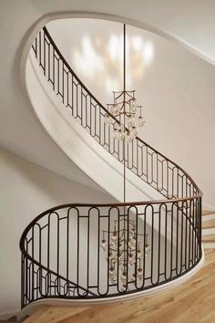 a spiral staircase with chandelier and wooden floors