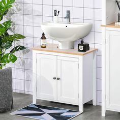 a white sink sitting on top of a wooden cabinet next to a potted plant