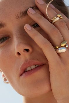 a close up of a person holding their hand to her face with rings on it