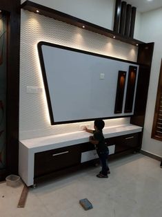 a young boy standing in front of a large tv screen on top of a wall