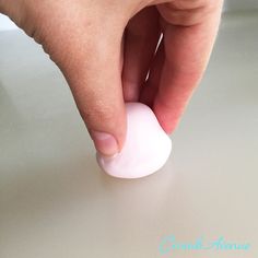 a hand holding a white object on top of a table