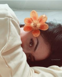 a woman laying on top of a bed with a flower pinned to her headband