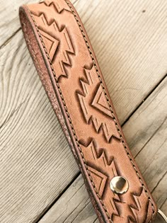 a leather keychain with an arrow design on it sitting on a wooden surface