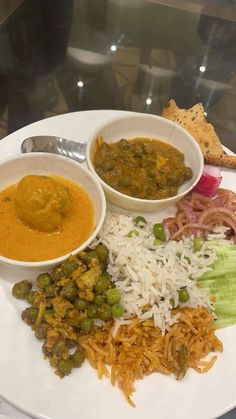 a white plate topped with rice, beans and veggies next to bowls of sauce