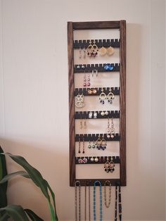 a wall mounted jewelry rack with several pairs of earrings hanging from it's sides