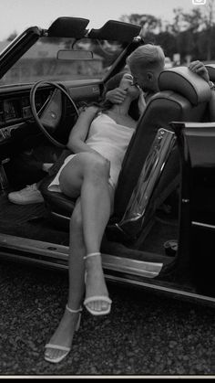 a woman sitting in the back of a car talking on a cell phone with her legs crossed