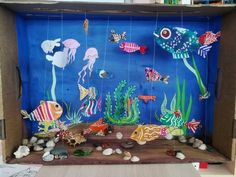 a cardboard box filled with different types of sea animals and fish on blue wallpaper