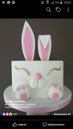 a cake with white frosting and pink bunny ears on the top, sitting on a plate