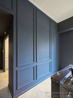 an empty kitchen with blue cabinets and marble counter tops, along with stainless steel appliances