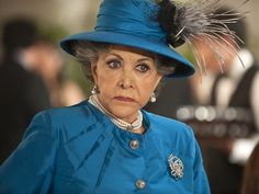 an older woman wearing a blue hat with feathers on it