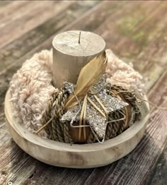 a wooden bowl filled with different types of items on top of a wooden table next to a candle