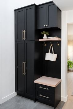 a closet with black cabinets and white bags