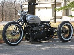 the motorcycle is parked on the side of the road in front of some trees and grass