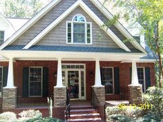 a brick house with black shutters and white trim on the front door is shown