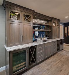 a large kitchen with wooden cabinets and marble counter tops, along with wine glasses on the shelves