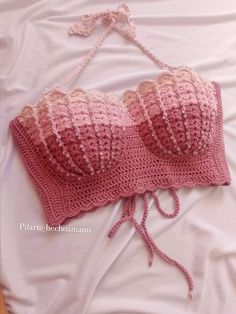 a crocheted bralet laying on top of a bed next to a pillow