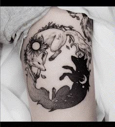 a woman's arm with a tattoo on it that has two cats and a moon