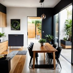 a dining room table with black chairs and plants