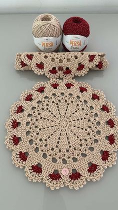 two balls of yarn sitting on top of a crocheted doily next to each other