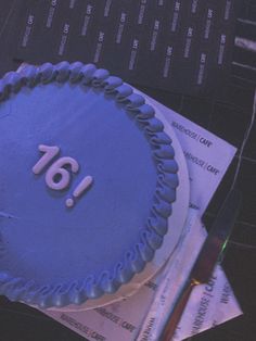 a blue frosted cake with the number sixteen on it