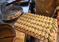 a person holding a tray with dumplings on it