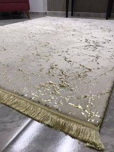 a white rug with gold fringes on the floor in a living room or bedroom